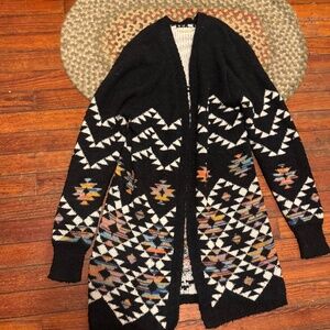 Stylish black cardigan with vibrant geometric patterns. Cozy and chic design. Pe